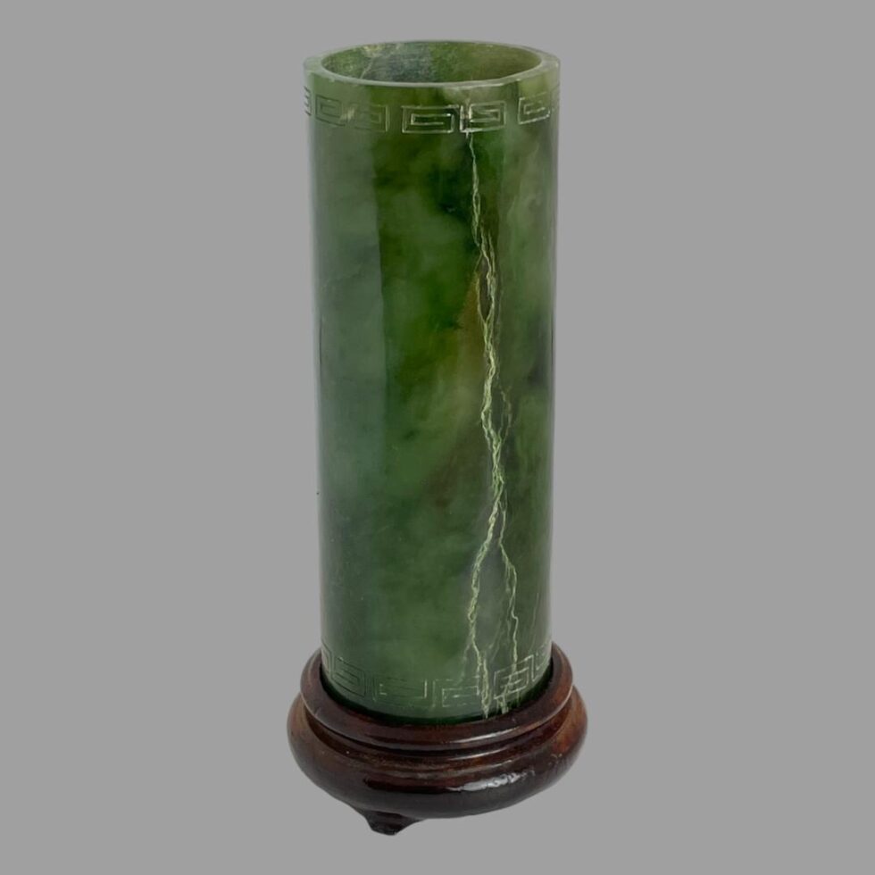 Photo of the side of jade brush pot without any decoration. There appears to be a natural crack running down the right hand side however, this is surface only and does not go through to the inside. The pot is still displayed on its stand