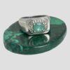 Main photo of modern silver emerald ring displayed on a small oval polished malachite with the ring front forward facing. This is a nice chunky ring with gemstone setting - quite unusual combination. The green of the emerald is a paler shade which works nicely with the silver.