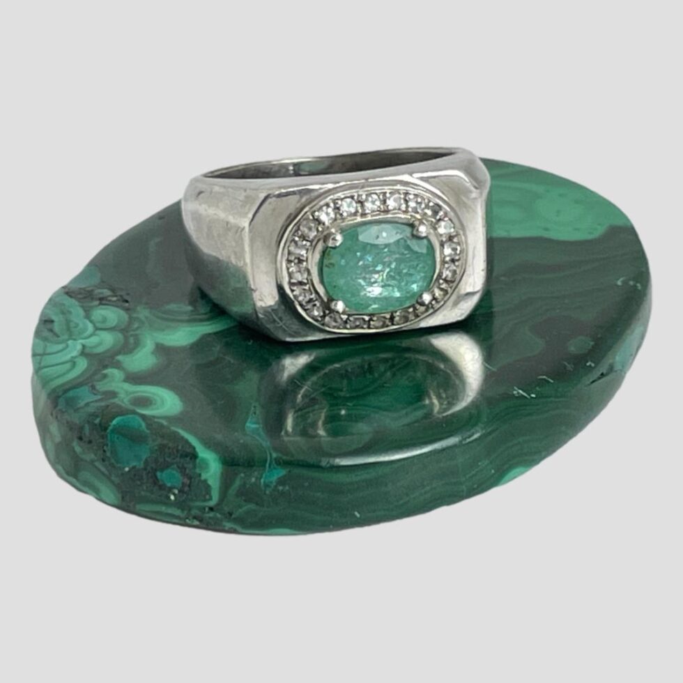 Main photo of modern silver emerald ring displayed on a small oval polished malachite with the ring front forward facing. This is a nice chunky ring with gemstone setting - quite unusual combination. The green of the emerald is a paler shade which works nicely with the silver.