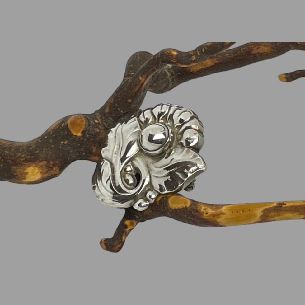 Photo of Jensen floral brooch still displayed perched on a dried cherry twig this time with the brooch front facing to the top left.