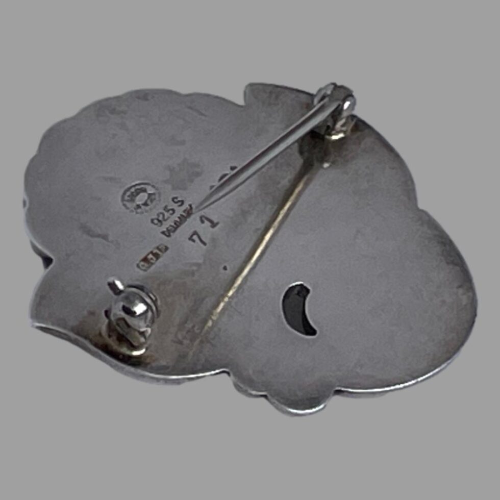 Photo of Jensen floral brooch laid flat and face down with the pin open.