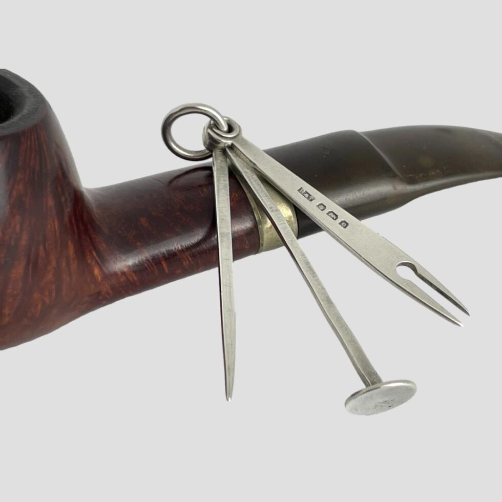 A close up of the Edwardian pipe cleaning set still shown leaning against an old smokers pipe.