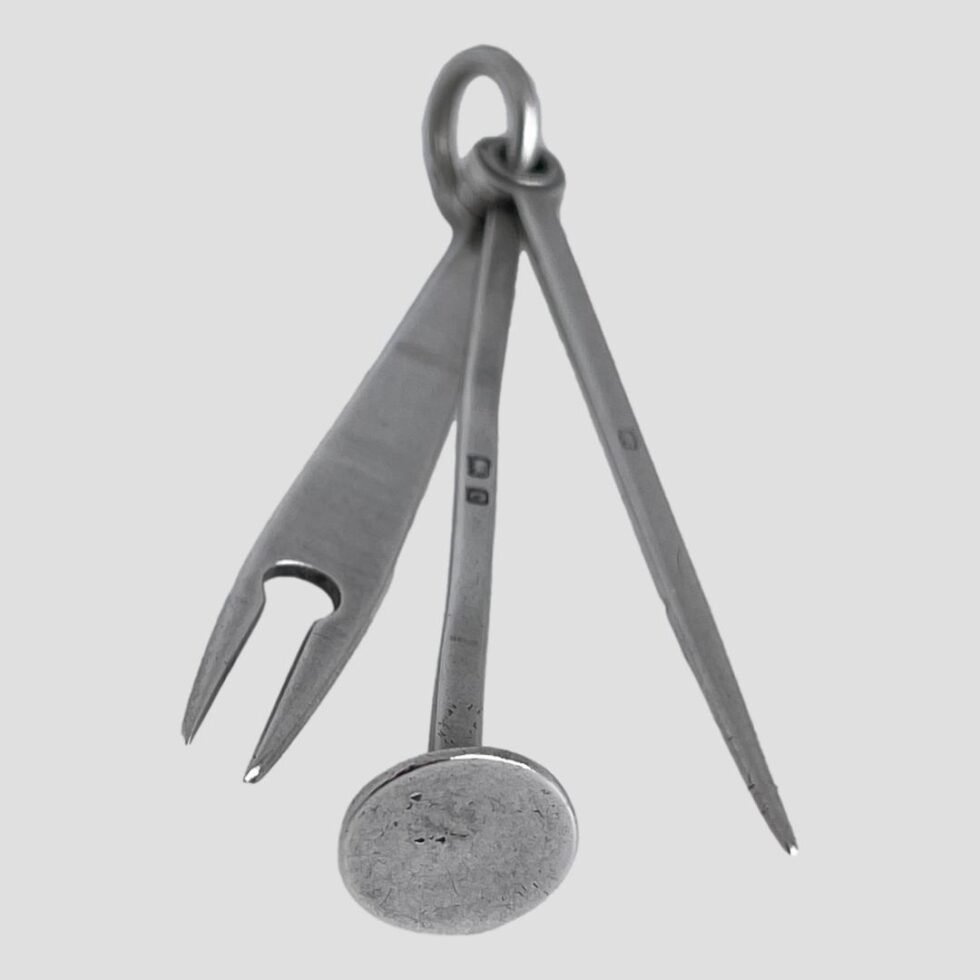 Photo of the tools laid out in fan like manner with the ring clasp at the top centre. The short hallmarks on the pick and tamper is visible.