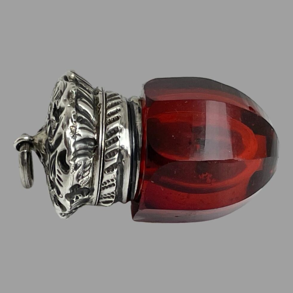 Photo of smelling salts bottle displayed on its side on a flat surface. The silver top end is on the left.