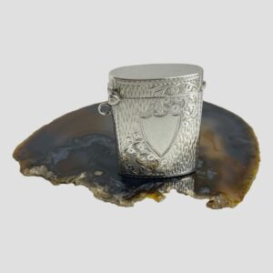 Main photo of Edward VII silver vesta displayed on top of a slice of agate and shown with the empty shield cartouche in the foreground.