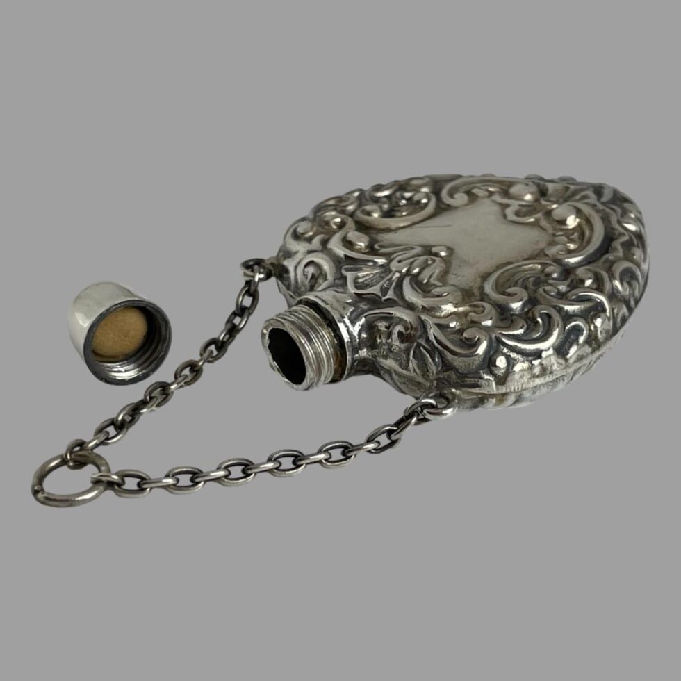 The heart scent bottle is now laid flat with the top removed and chain extended out.