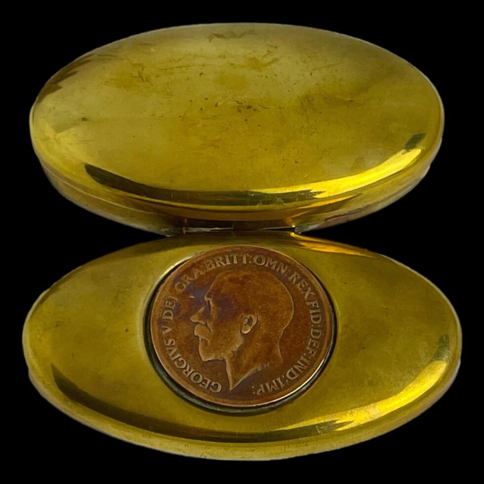 Photo of the antique miners snuff box displayed fully opened and laid flat exposing the top of lid with coin and the base of the box at same time.