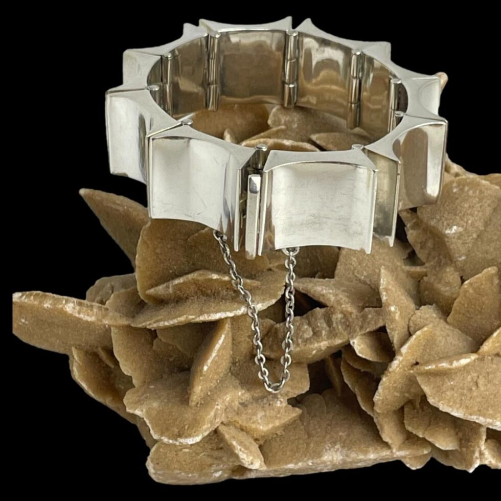 Photo of Taxco bracelet still displayed on top of a rock of natural desert sand rose and shown with the whale tail clasp and safety chain in the centre foreground.