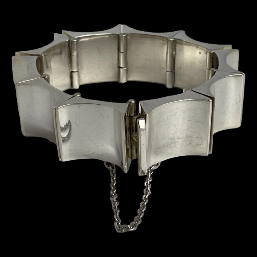 Photo of Taxco concave rectangle bracelet displayed on a flat surface with the clasp area in the centre foreground. The clasp is shown closed with the safety chain hanging below.