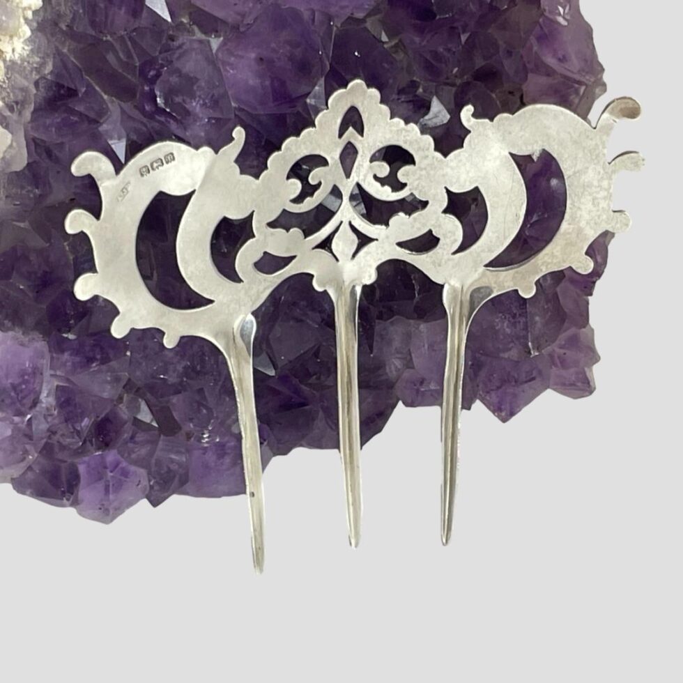 Photo of Edwardian silver hair comb shown upright and from the back. The full hallmark is visible on the top left of the comb.