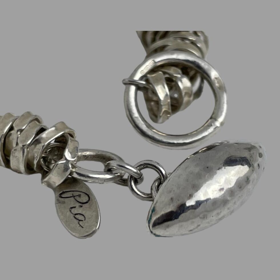 Close up photo of the ring clasp with the hallmark just visible and the makers original tag (Pia)