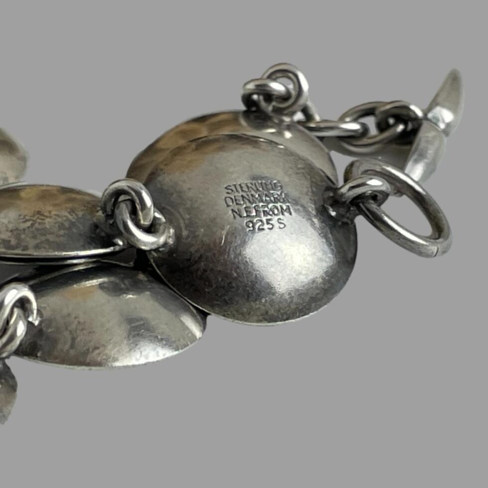 Close up photo of the hallmark to the back of one of the disc link backs. The back of the bracelet links are all convex. The hallmark reads 'Sterling Denmark N E From 925 S