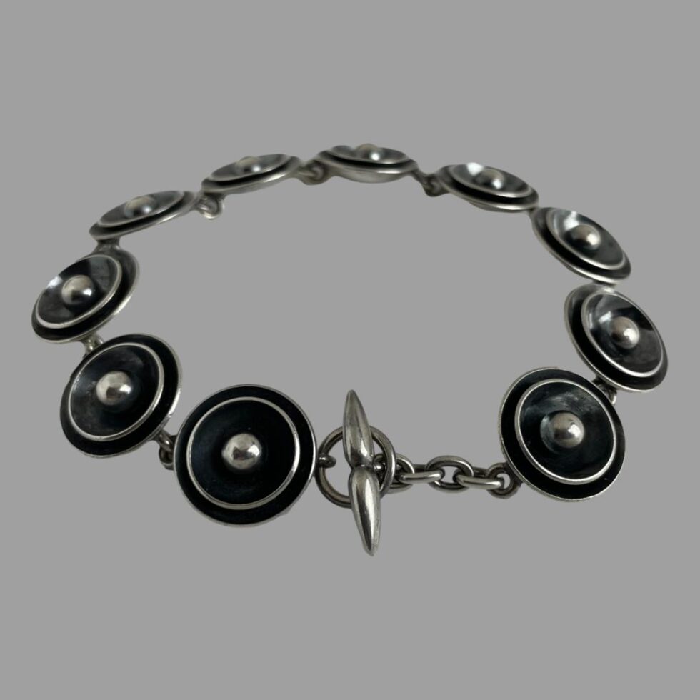 Photo of the bracelet displayed on a flat surface with the clasp closed and bracelet laid out in a circle. The whale tail clasp end is in the centre foreground.