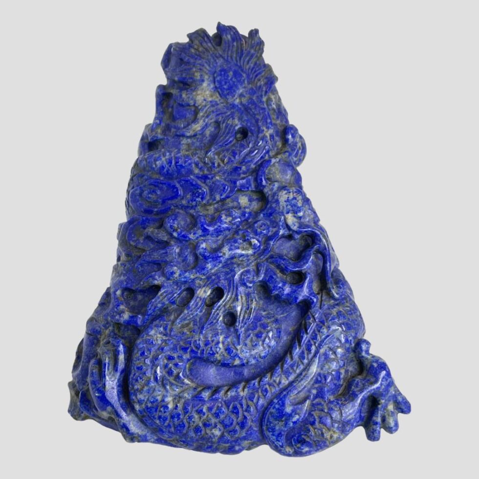 Main photo of vintage carved lapis dragon displayed with the front of the dragon on display. The tip of the dragons tail is at the top of the carving with its front legs on the bottom left and right. The Oriental dragon has a long snakelike body, this one winds around the pyramid shape, reaches the bottom and is now back on the ascent. Its head is near centre of the carving front and looking up to the summit. A lovely gift item.