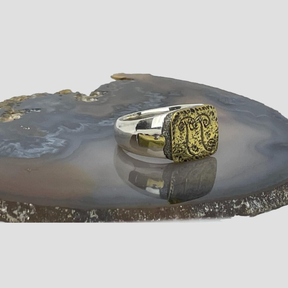Photo of the Medieval floral design ring this time with ring front facing the bottom right corner and showing the shorter of the gilt alloy strips set in the silver band.