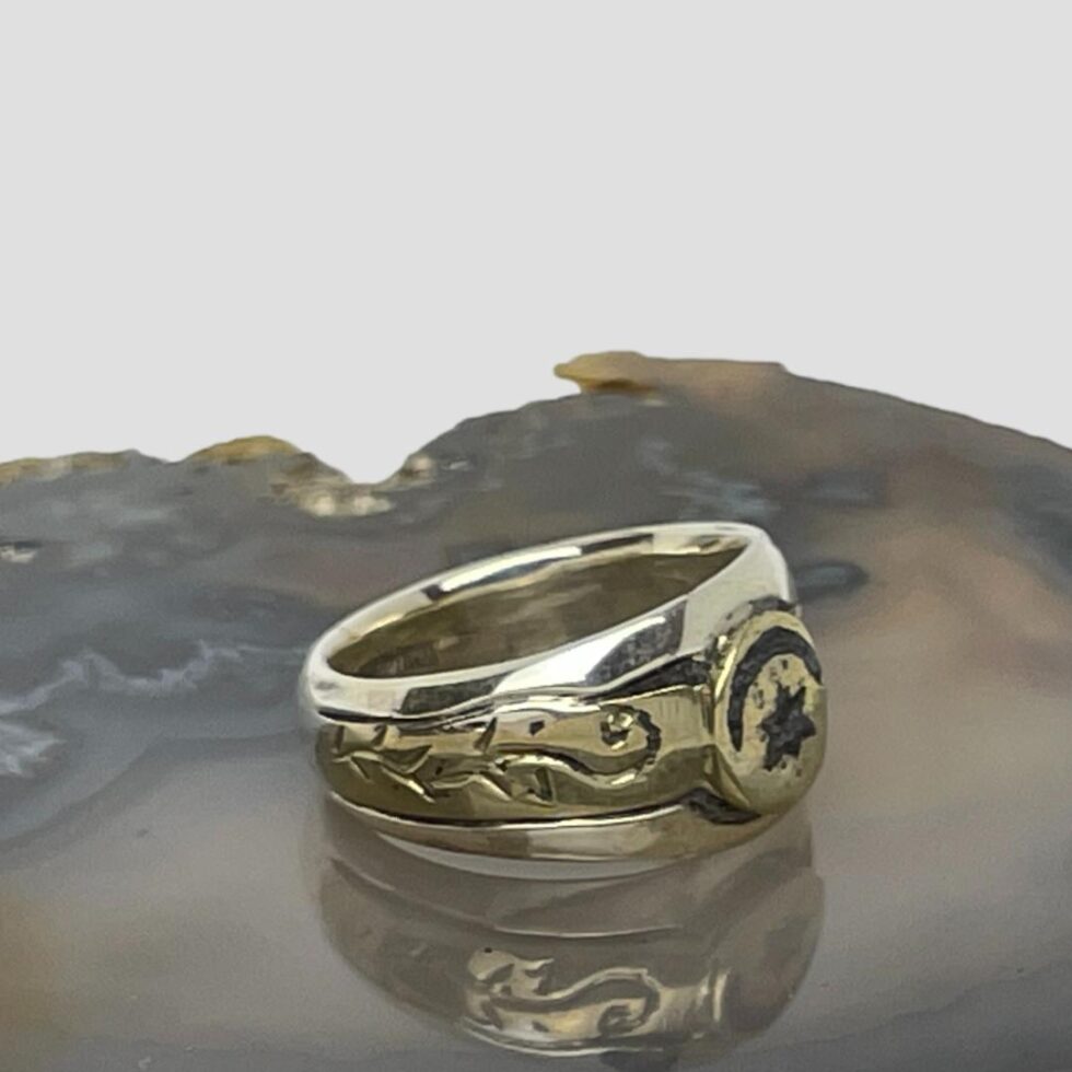 Photo of the Medieval bronze fragment ring facing to the bottom left corner showing the embossed design detail on the shoulders.
