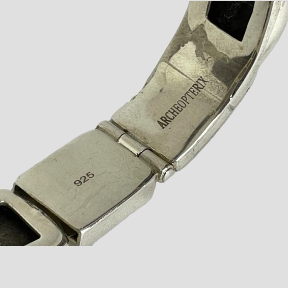 Close up photo of the hallmark and designer 'Archeopterix' stamp on the back of the clasp area.