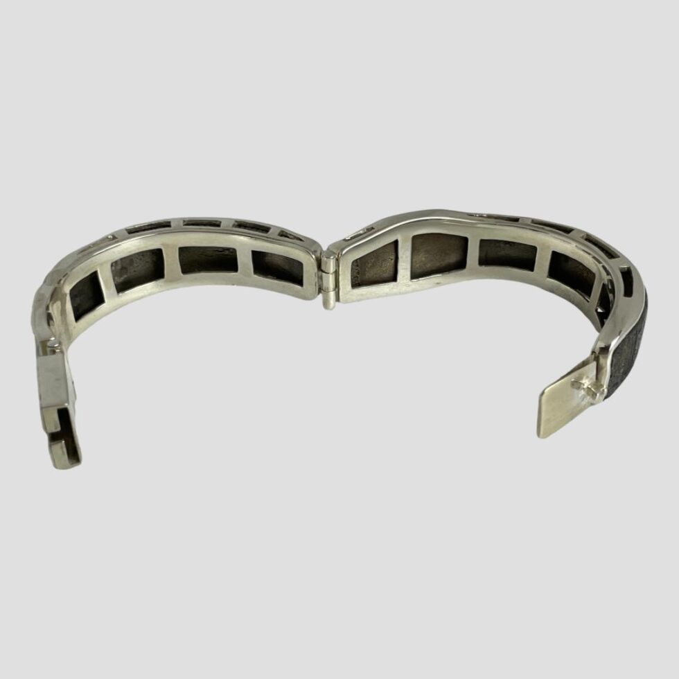 Photo of Viking snake bracelet displayed on a flat surface with the bracelet shown fully open. The hinge part of the bracelet is between the head and tail of the snake and the bracelet opens up quite wide.