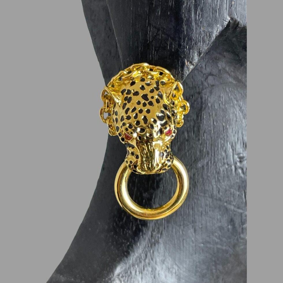 Photo of one of the leopard door-knocker earrings displayed on an earlobe of a black wooden display model.