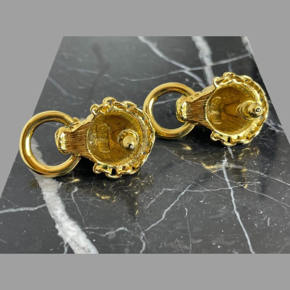 Photo of the back of the leopard door-knocker earrings displayed side by side on their side on top of a block of black marble. The rings are on the left and the 89 FM mark is visible to back of both earrings.