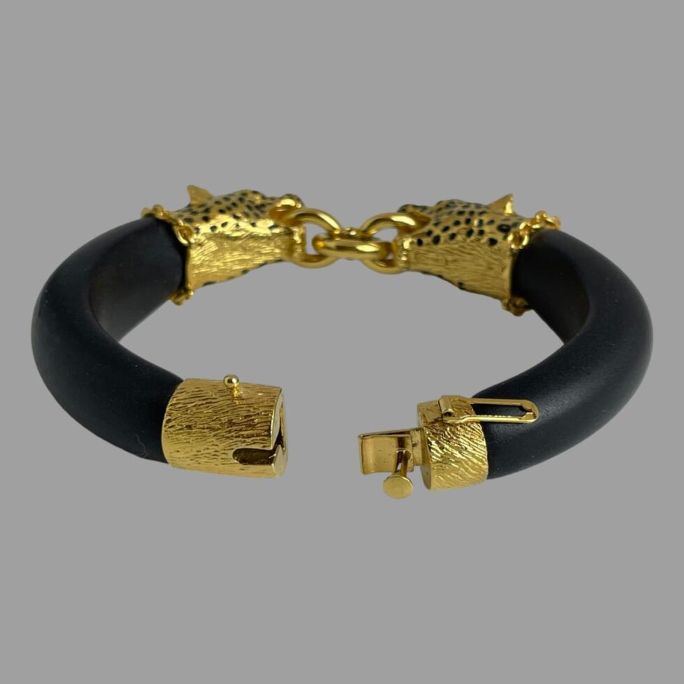 Photo of the leopard head bracelet only displayed on a flat surface with the the clasp area in the centre foreground and shown open. The safety catch is on the right hand clasp end.