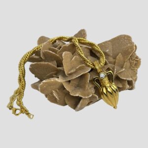 Main photo of amphora pendant/brooch &chain displayed draped over a rock of natural desert rose. The amphora is on the right facing forward and the double rope twist chain is laid over the top of the sand rock with the undone clasp on the left.