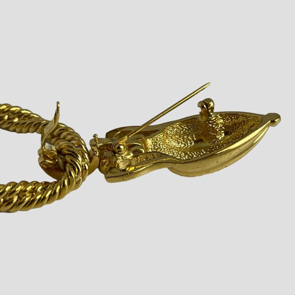 A close up photo of the pendant/brooch displayed face down from a side angle. Both the pin of the brooch and bail of the pendant are shown open.