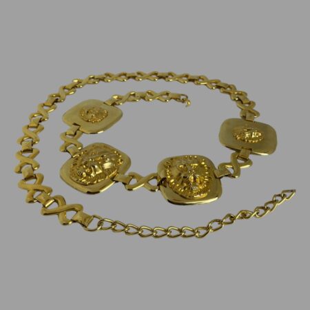 Main photo of Escada golden lions belt displayed in a coiled fashion on a flat surface. The 4 gilt plates with the lions heads are on one side of the belt so it can be worn at the front or to the side. The lions head plates are coiled at the centre of the image.