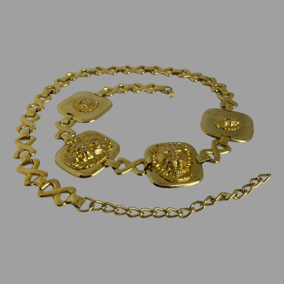 Main photo of Escada golden lions belt displayed in a coiled fashion on a flat surface. The 4 gilt plates with the lions heads are on one side of the belt so it can be worn at the front or to the side. The lions head plates are coiled at the centre of the image.