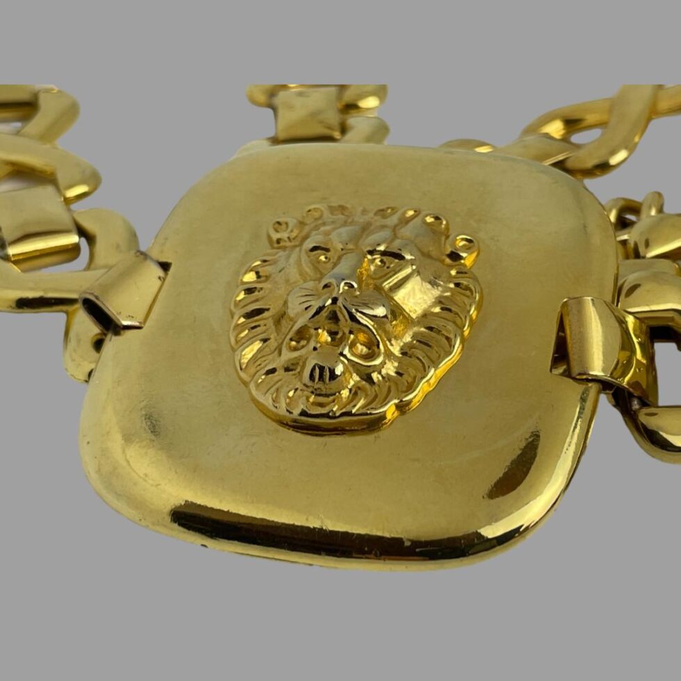 A close up photo of one of the gilt panels with a smaller lions head. The smaller head has a smaller mane.