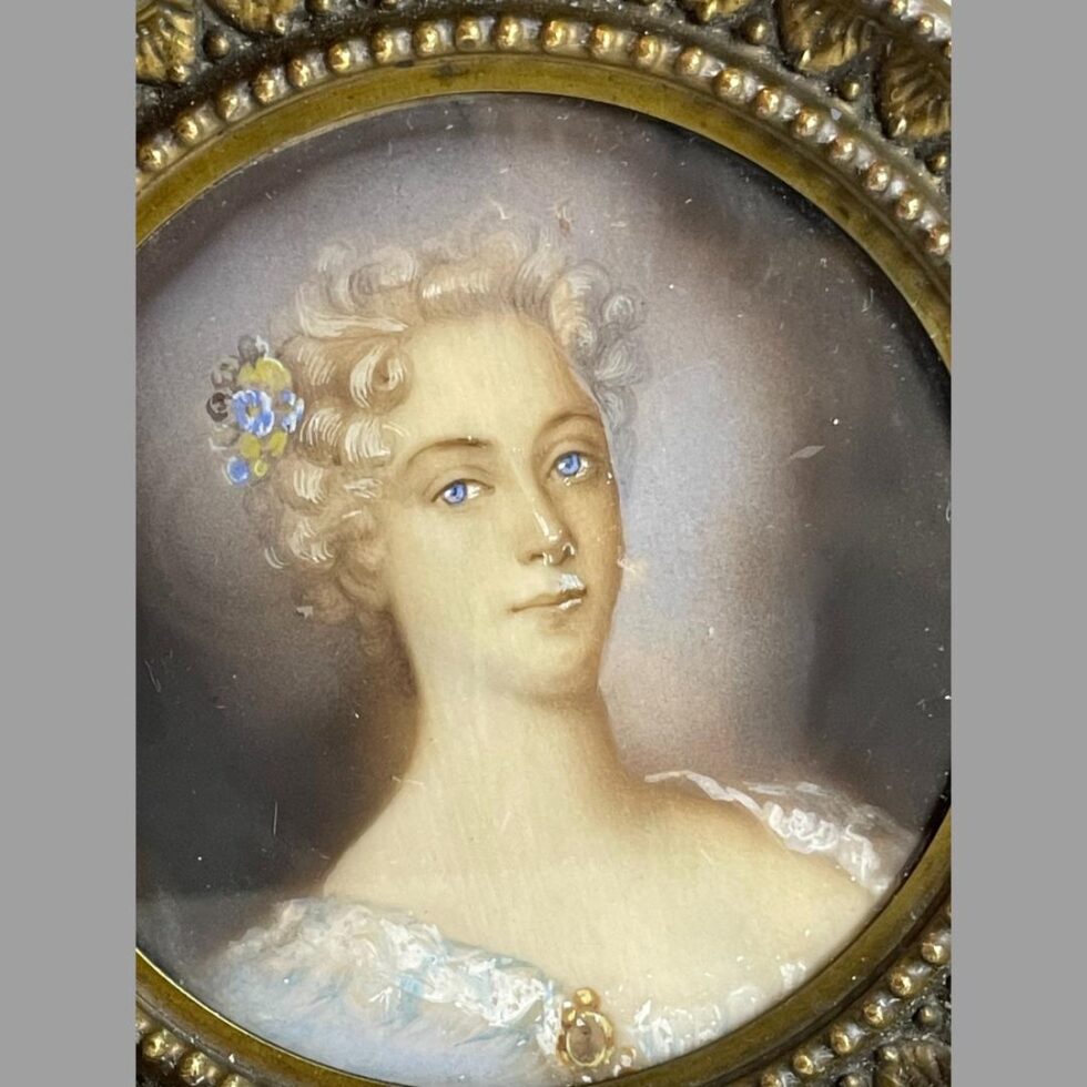 A close up photo of the female subject in the French miniature prtrait. The photo has been taken as she would appear if hung from the ring hook which is leaning slightly back.
