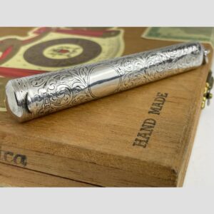 Main photo of antique silver cheroot case displayed on the corner of an old wooden cigar box. The lid end of cheroot is slightly in the foreground on the left and the empty cartouche is visible. The full hallmark is also visible just below the lid.