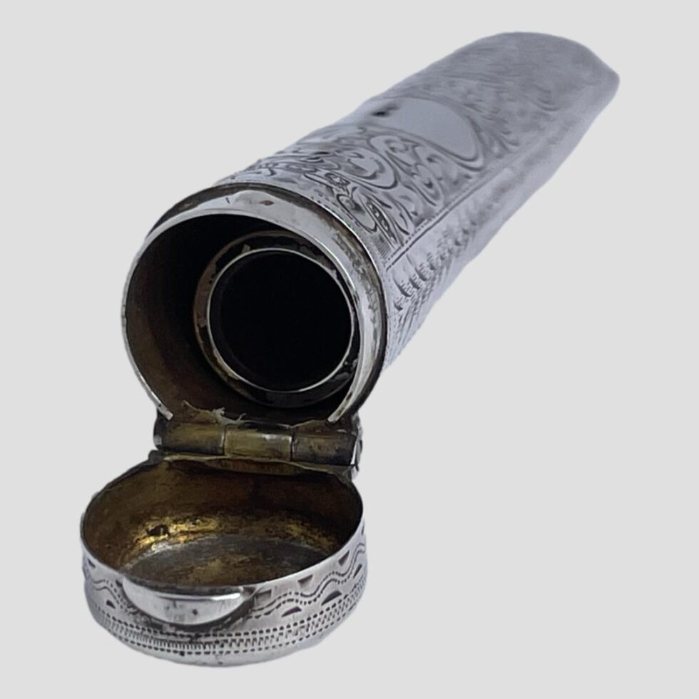 Photo of cheroot case displayed with the opening end in the bottom left corner. The lid is open and the cheroot holder is just visible inside.