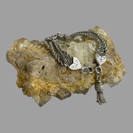 Main photo of Victorian Albertina chain bracelet displayed draped over a rock of natural river quartz with the bracelet front with the heart ends, clasp and tassel in the foreground.