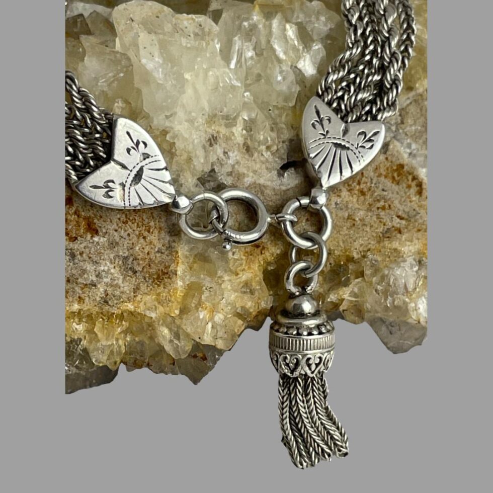 A close up photo of the heart shaped ends of the bracelet and the tassel detail attached to the clasp.
