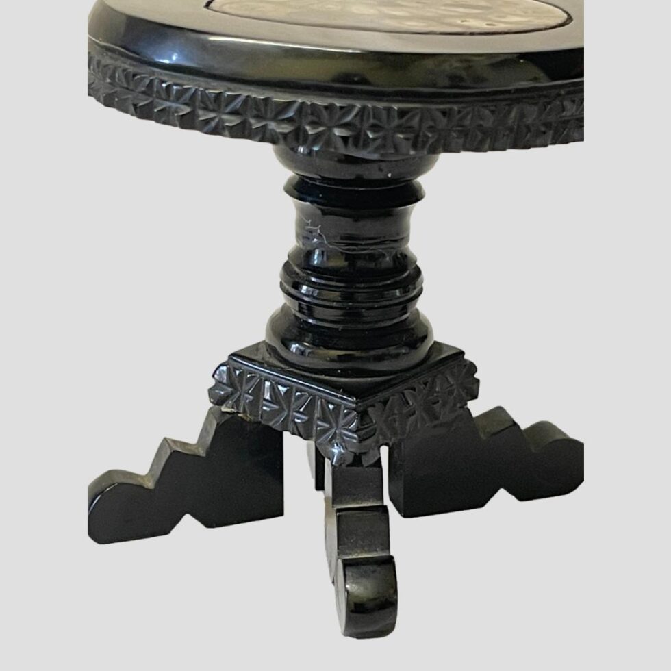 Photo of the table seen from an eye level and focusing on the carved detail of the jet.