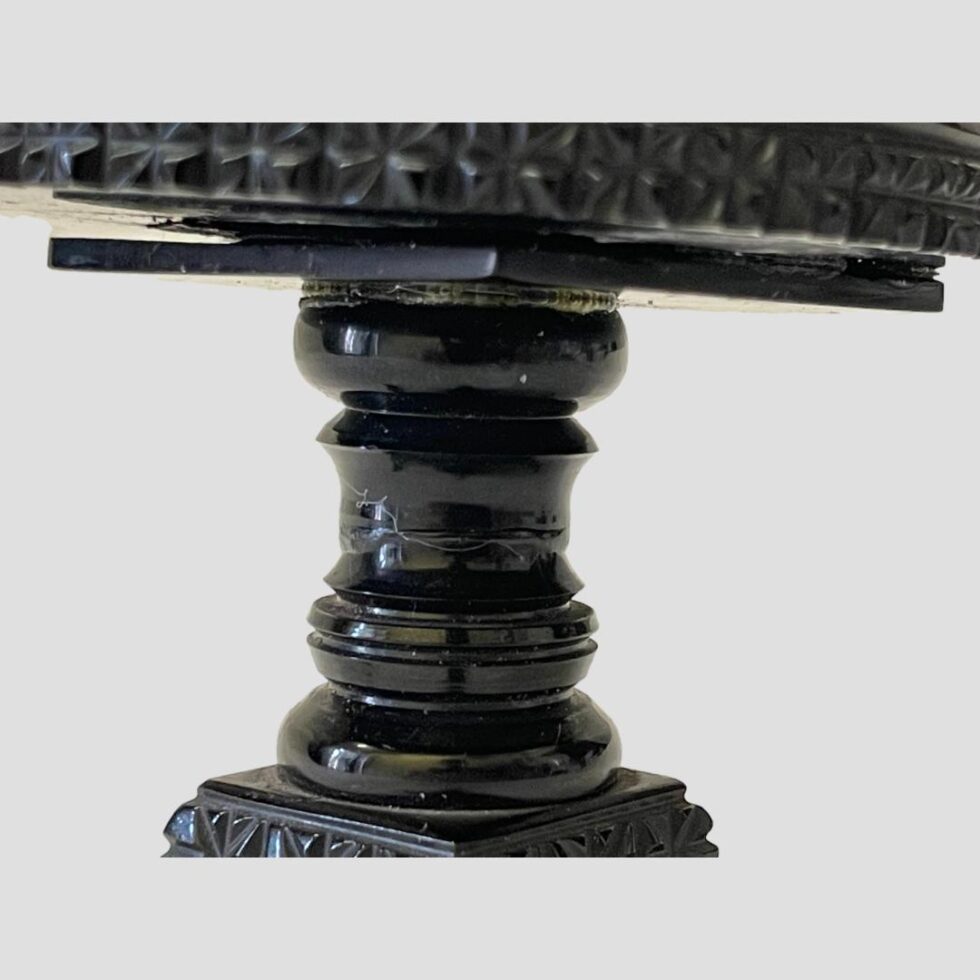 Close up photo of the area below the table top showing the carved pedestal.