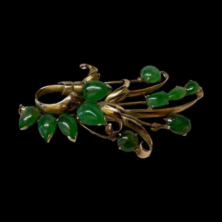 Main photo of 14kt jade spray brooch displayed horizontally long and against a black background. The brooch is a stylised spray of flowers with the gold as stems and jade pieces as flowers. The jade comes in round, oval and teardrop shapes and are a stunning apple green in colour - a sure sign of quality jade. It is beautifully created and can be worn any side up. A lovely gift item.