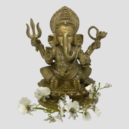 Main photo of antique bronze Lord Ganesh shown against a light grey background and facing forward at the camera. There a spray of white orchids laid around his feet. This bronze has a golden hue and is very well presented.