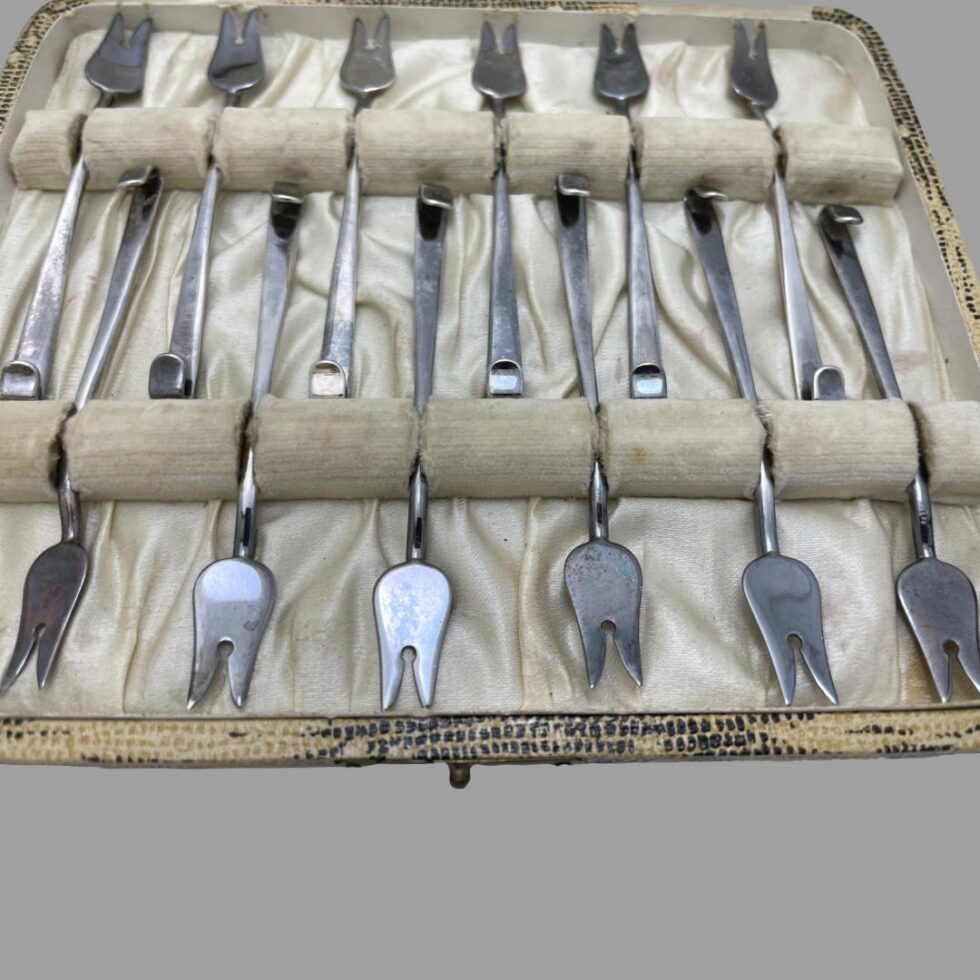Close up photo of all 12 cocktail forks displayed inside their fitted case.