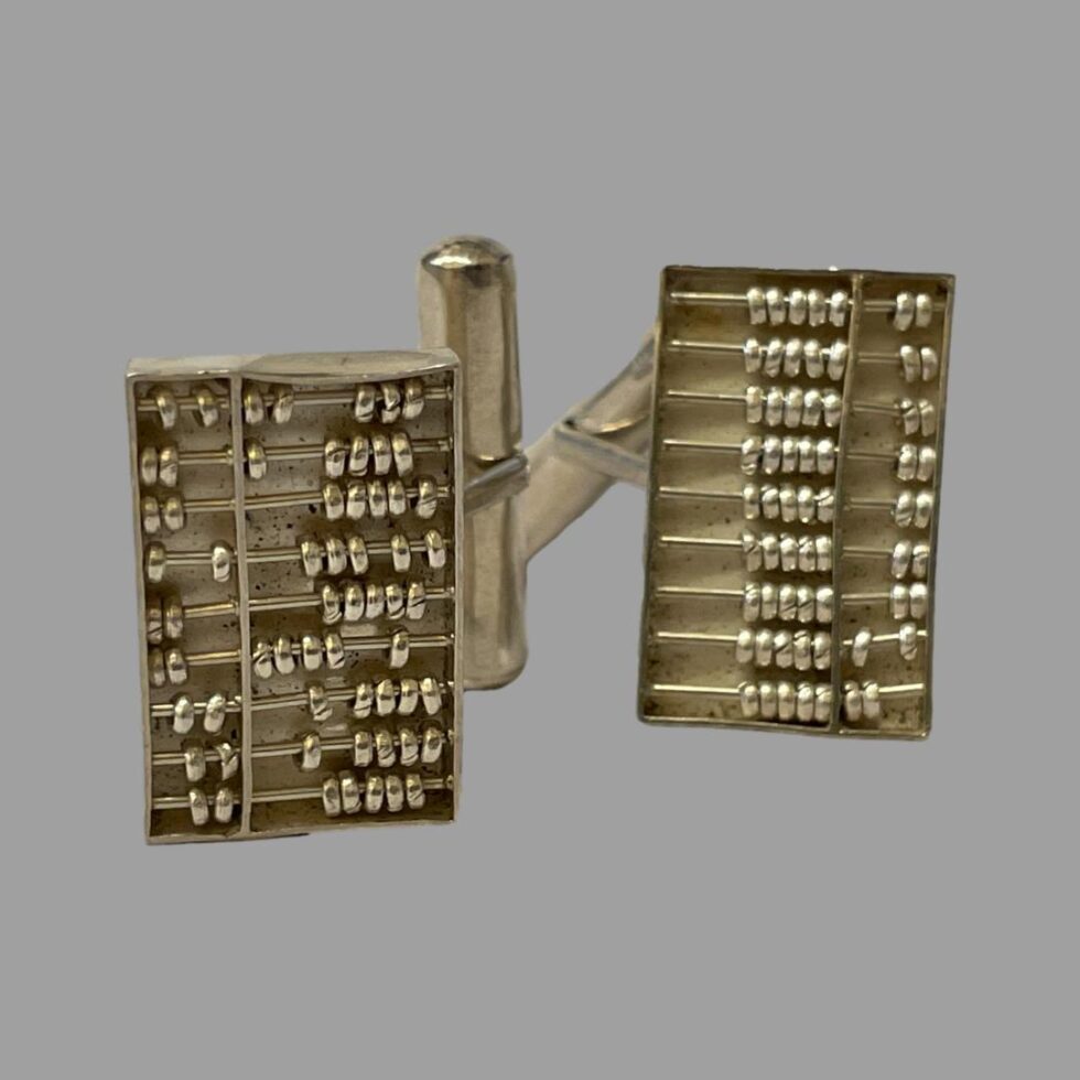 Photo of the abacus cufflinks this time displayed on their side. The cufflink to the left is showing the counters in random spacing whilst one on right has counters neatly in a row.