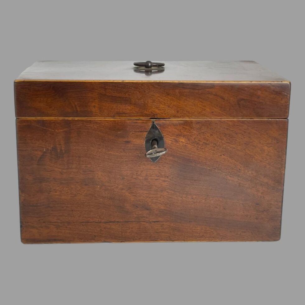 Photo of small antique tea caddy seen from the front with lid closed. The key is in the keyhole.