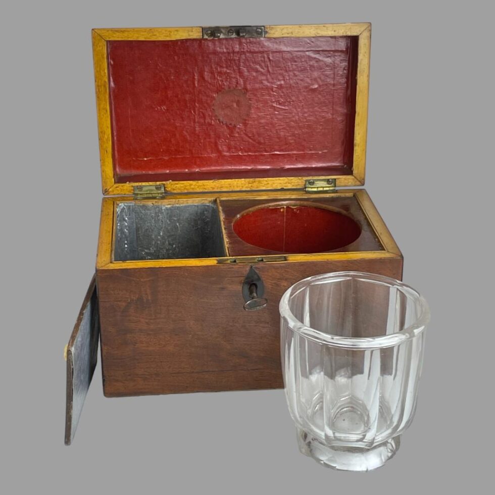 Photo of small tea caddy with the glass mixing bowl outside of its slot in front of the box and the lid to the caddy is off and leaning against the side. The zinc lining is visible .