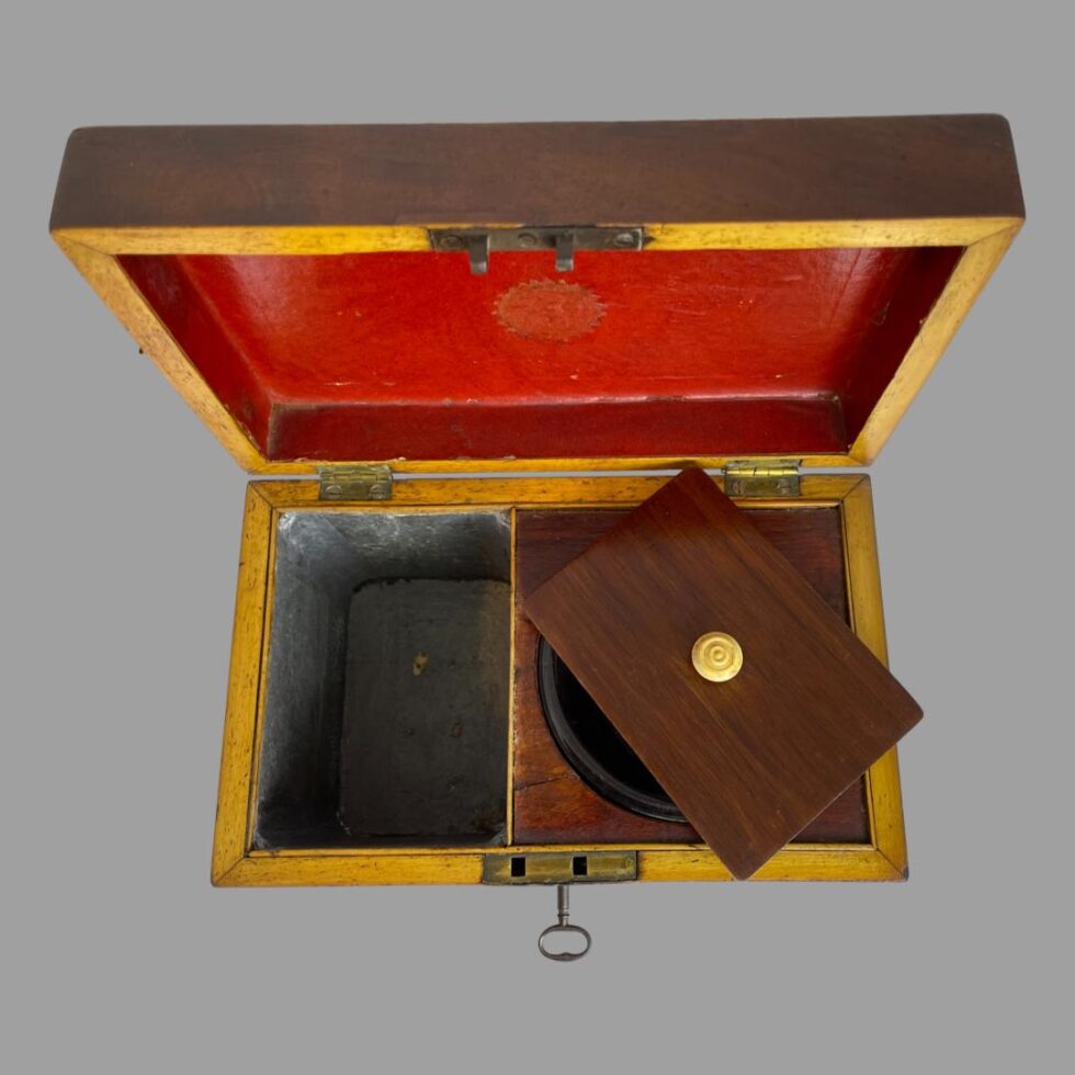 Photo looking straight down to the top of the tea caddy. The lid of the tea box is on top of the glass bowl and the zinc lining is visible.