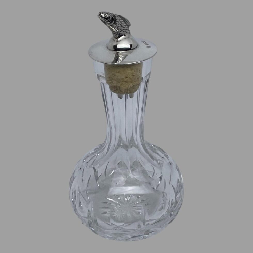 Photo of bitters bottle seen from a slightly raised angle looking diagonally downward. The salmon is more visible and the full hallmark can be seen to the right of the fish.