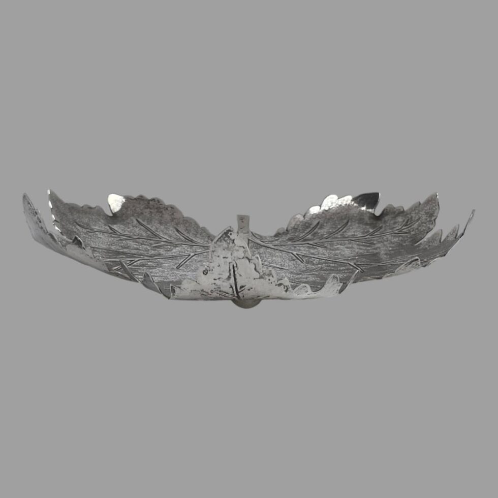 Photo of the silver leaf pin dish seen with the top tip of the leaf in the centre foreground. One ball foot is just visible below and the upward and inward curve of the leaf tips is clearly visible.