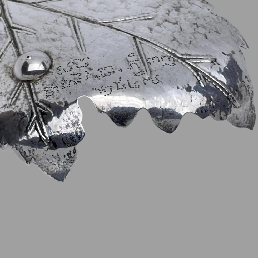 Close up photo of the pierce work writing on the base of the silver leaf dish. The pierce work gives an impression of having been eaten by leaf worms. Very neat, very sweet !