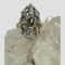 Main photo of Edwardian sapphire diamonds ring displayed on top of a rock of natural quartz crystal with the ring front forward facing. The oval cut sapphire in the centre has its own setting in gold with 4 teeth holding it in place. The elaborate silver front is added to the cover the rest of the rings face with the 10 old rose cut diamonds spaced out evenly throughout. The ring is vertically long with pointed top and bottom. The back of the elaborate face is yellow gold so the silver work at the front is like a shield or mask. Nice split band at the shoulders add an elegant touch,