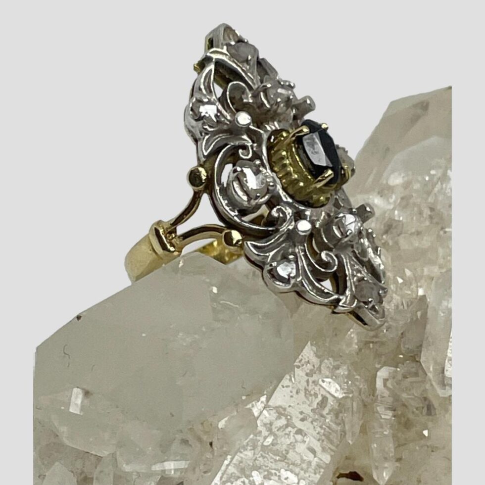 Photo of sapphire diamonds ring still displayed on a rock of natural quartz crystal with the ring front facing to the right and slightly upward to the top right corner. The split band at shoulder is clearer here.