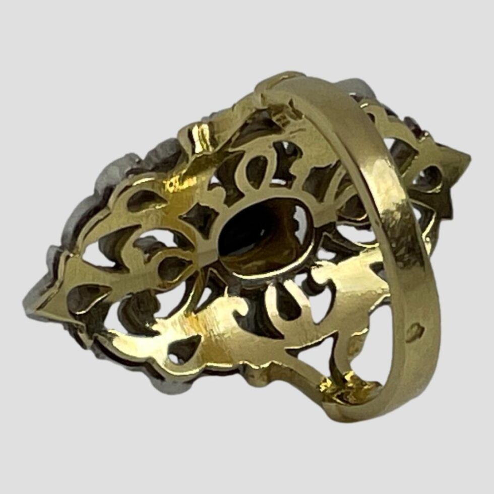 Photo of the back of the ring showing in gold the silver front face. The ring is on its side. The single indent is visible to the outer band at back believed to be a hallmark.